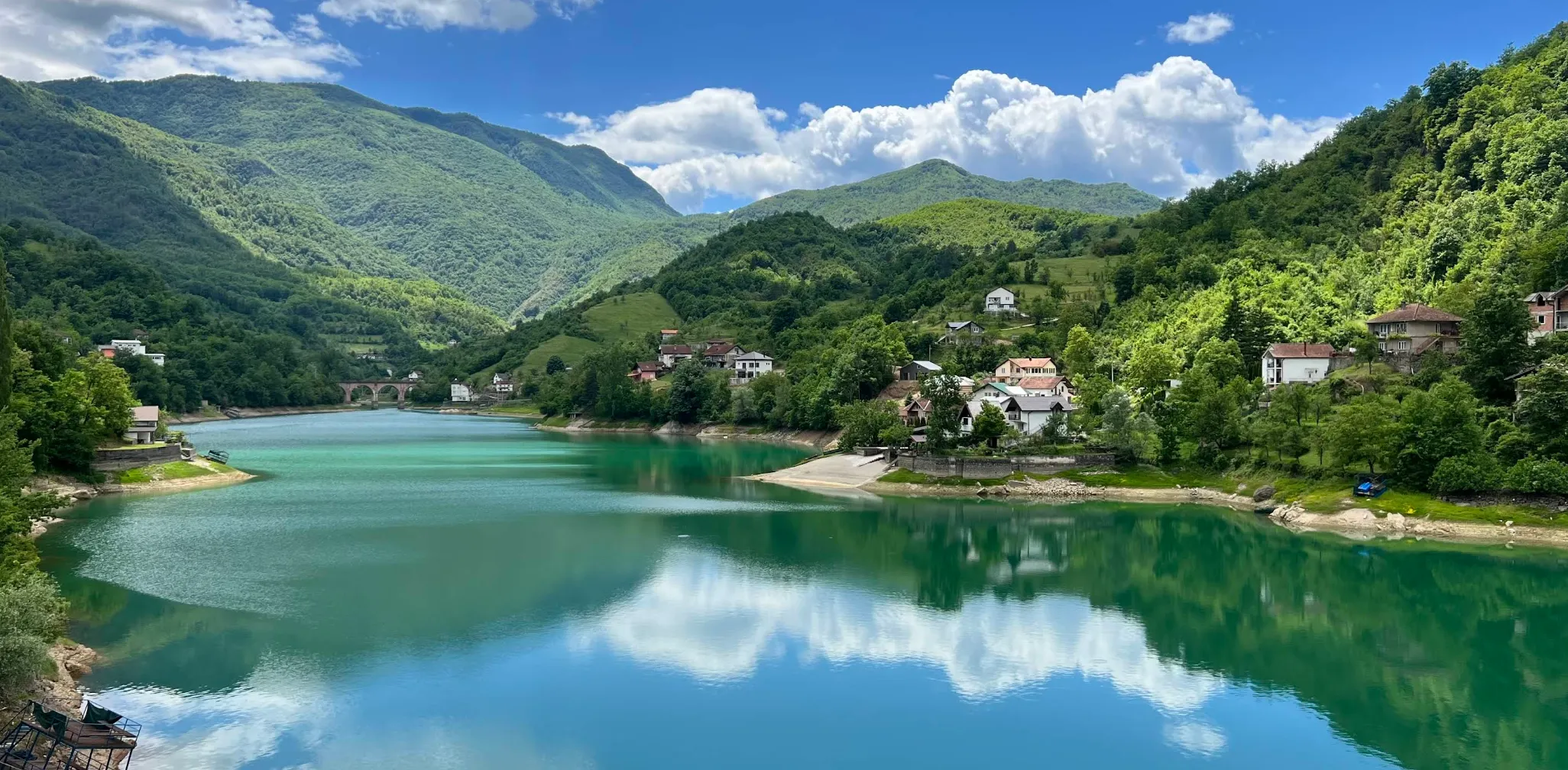 Mirna površina Jablaničkog jezera sa odrazom brda i obalnih kuća