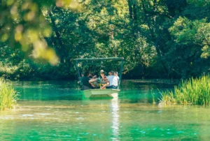 Turisti u vodi rijeke Une na Japodskim otocima, gusto zelenilo uz obalu