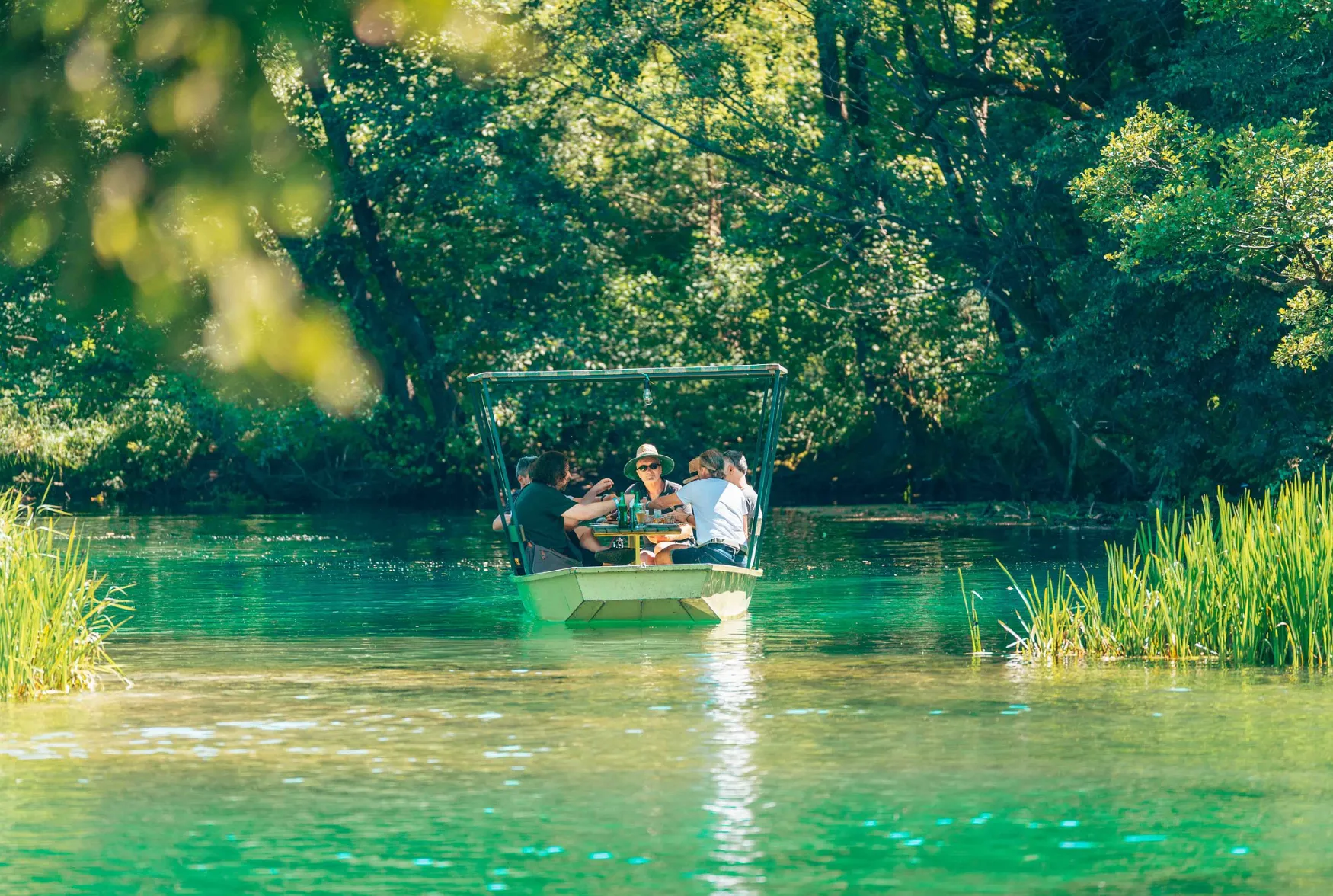 Turisti u vodi rijeke Une na Japodskim otocima, gusto zelenilo uz obalu