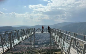 voje turista na staklenoj platformi vidikovca Fortica iznad Mostara, planinski pejzaž u pozadini