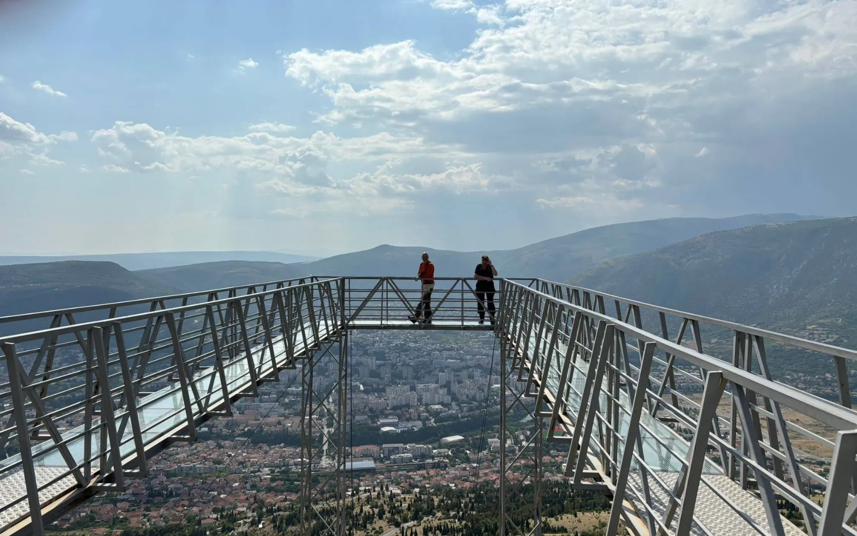 voje turista na staklenoj platformi vidikovca Fortica iznad Mostara, planinski pejzaž u pozadini