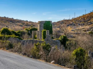 View of the Old Town Hutovo with an ivy-covered tower beside the local road