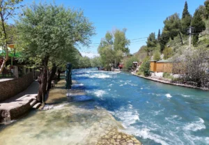 Brzi tok bistre rijeke Bune kroz Blagaj, kamene kuće i zelenilo uz obalu