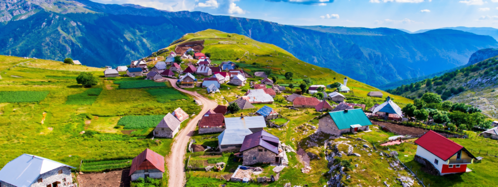 Selo Lukomir Konjic Ovo izgleda kao cover/hero slika. Evo prijedloga: Alt: Ptičja perspektiva sela Lukomir na planini Bjelašnici, tradicionalne kamene kuće na zelenoj visoravni s pogledom na planinski kanjon