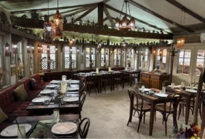 Enterijer restorana Inat kuća u Sarajevu, tradicionalno uređenje sa drvenim stolovima i stolicama