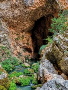 Natural spring of the Tihaljina River surrounded by rocks and lush greenery