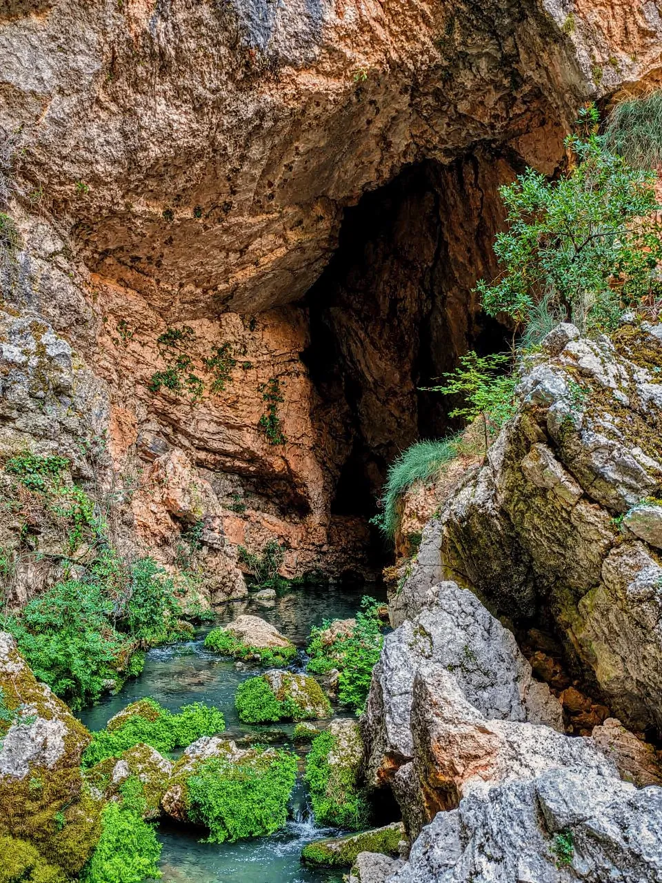Natural spring of the Tihaljina River surrounded by rocks and lush greenery