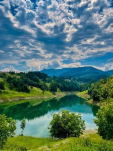 Reflection of clouds and forest in the waters of Hadžije Lake on a sunny day