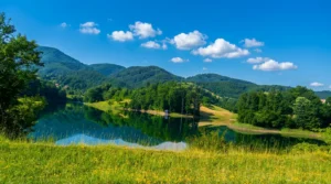 Grassy shoreline and the landscape of Hadžije Lake under the open sky