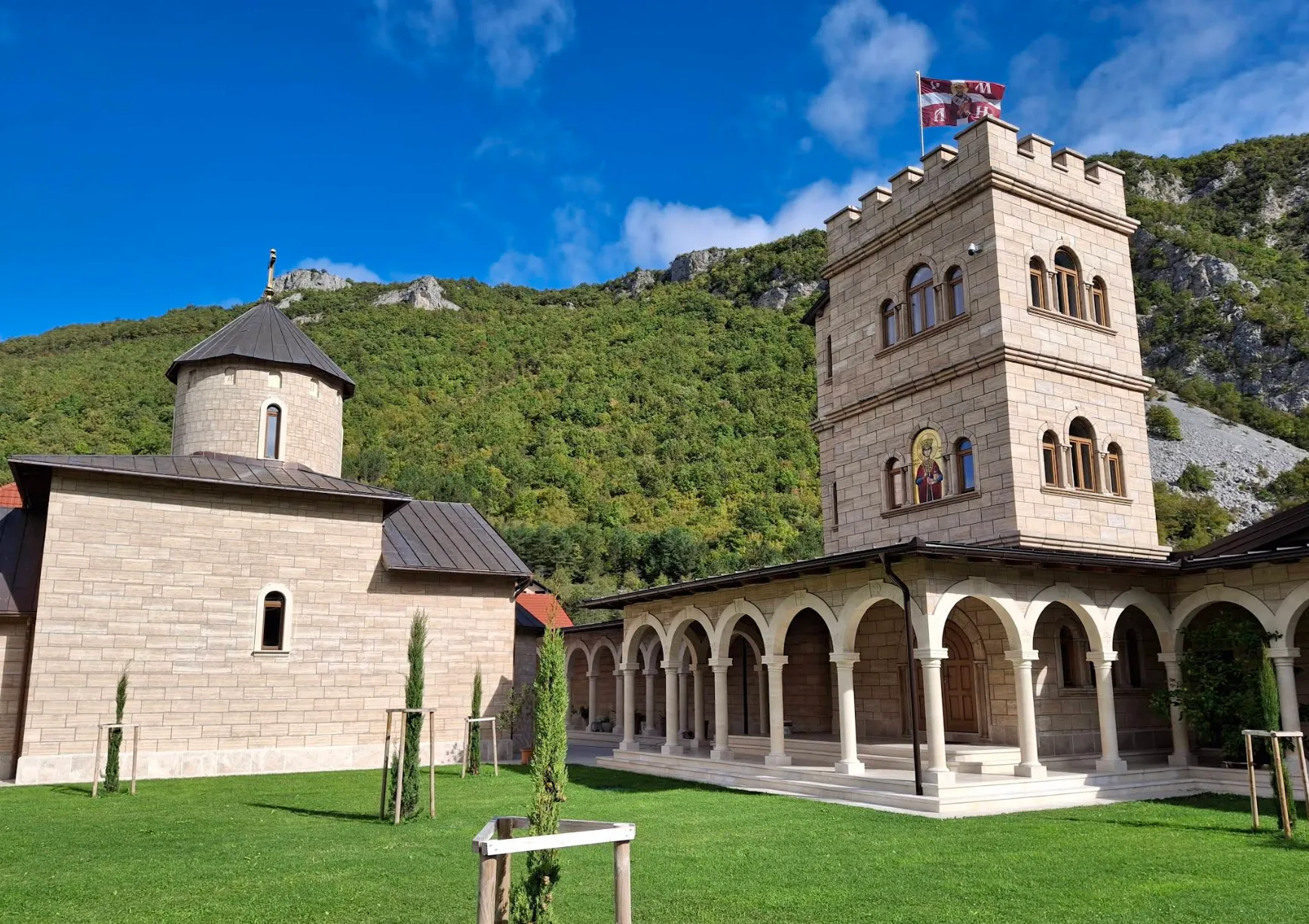 Pravoslavni manastir u Martin Brodu, kamena crkva sa zvonikom okružena zelenilom i planinama