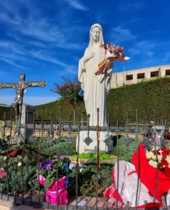 Kip Gospe Međugorske okružen cvijećem i križevima u Međugorju
