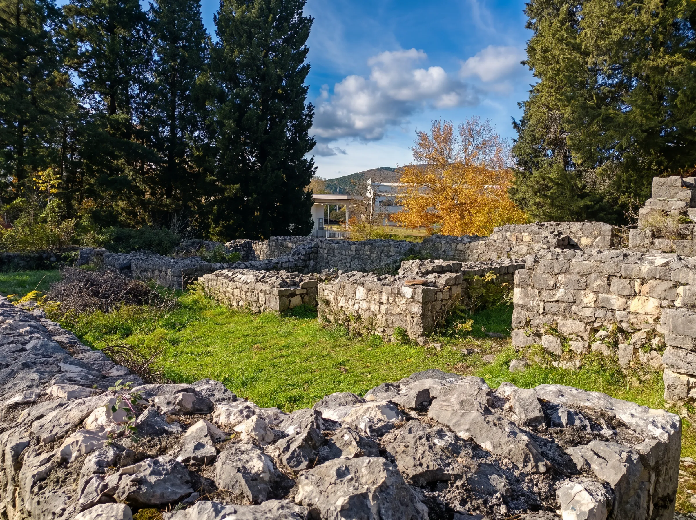 Ruins of a late antique Roman villa rustica up close, with grassy interior areas and distinctive stone structures under a sunny sky