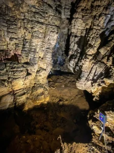 Pogled na karakteristične horizontalne nabore i reljefne teksture na zidovima pećine Rastuša, nalik na saljeve i kaskade, osvijetljene toplim žutim svjetlom