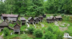  Tradicionalni drveni mlinovi na stupovima uz obalu Plivskog jezera kod Jajca, okruženi gustim zelenilom