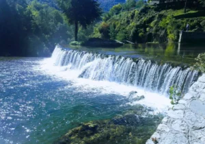 Plivski vodopad u Jajcu okružen gustim zelenilom, tirkizna voda u podnožju slapa