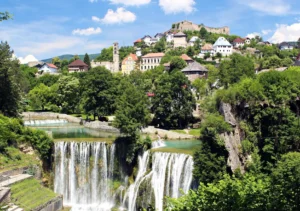 Panoramski pogled na Plivski vodopad u Jajcu sa starim gradom i tvrđavom na brdu u pozadini