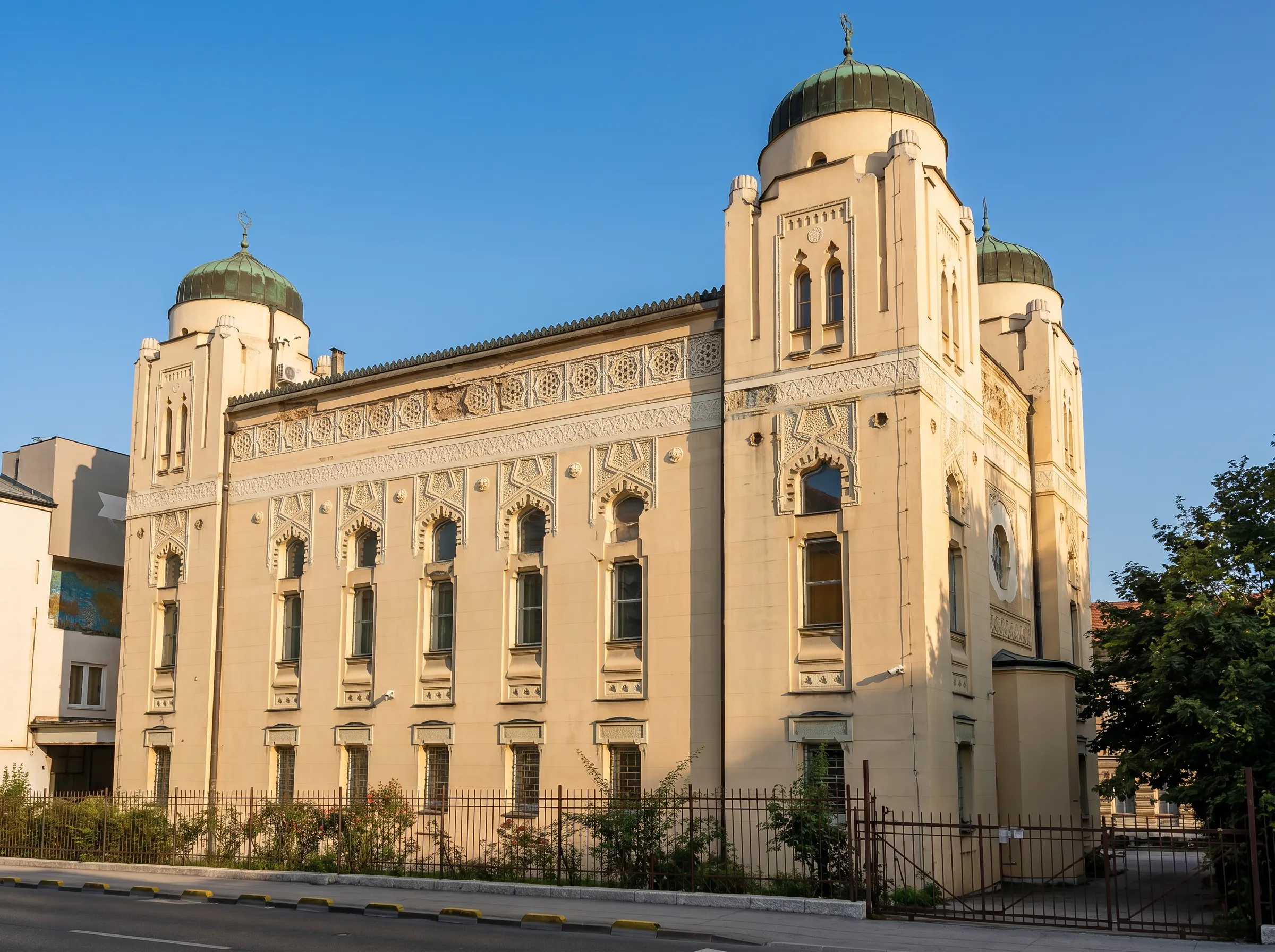 Krupniji kadar bočne fasade Aškenaske sinagoge u Sarajevu, sa prepoznatljivim orijentalnim prozorima, ukrasnim detaljima u pseudomaurskom stilu i karakterističnim ugaonim kupolama