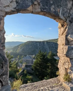 Pogled kroz kameni luk Starog grada Stolca na planinski pejzaž i dolinu u pozadini