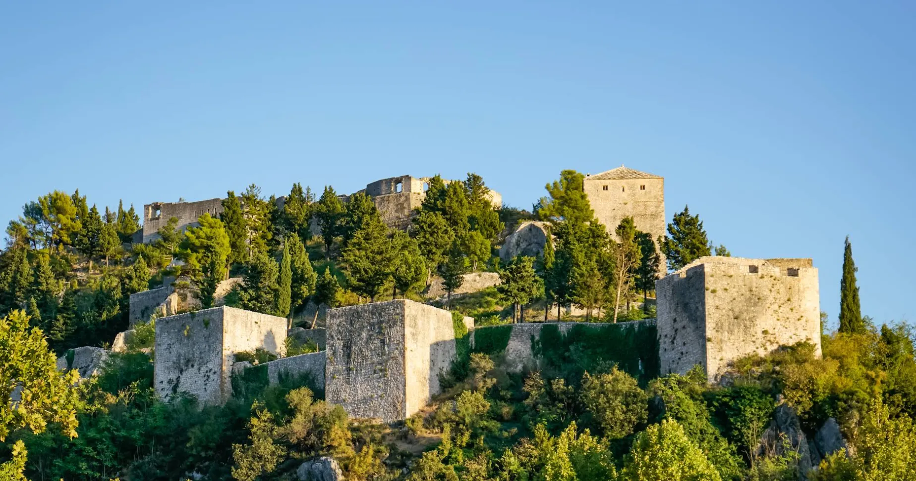 Panoramski pogled na kule i bedeme Starog grada Stolca okružene mediteranskim zelenilom