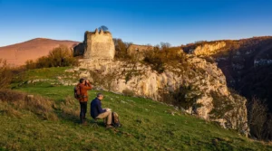 Hikers enjoy the break and the beautiful scenery with a view of the walls of Bočac Fortress