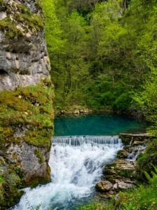 A close-up of the beautiful, intensely turquoise water of the hidden pool at the source of Bastašica, which foams over a concrete ledge and turns into a powerful white waterfall