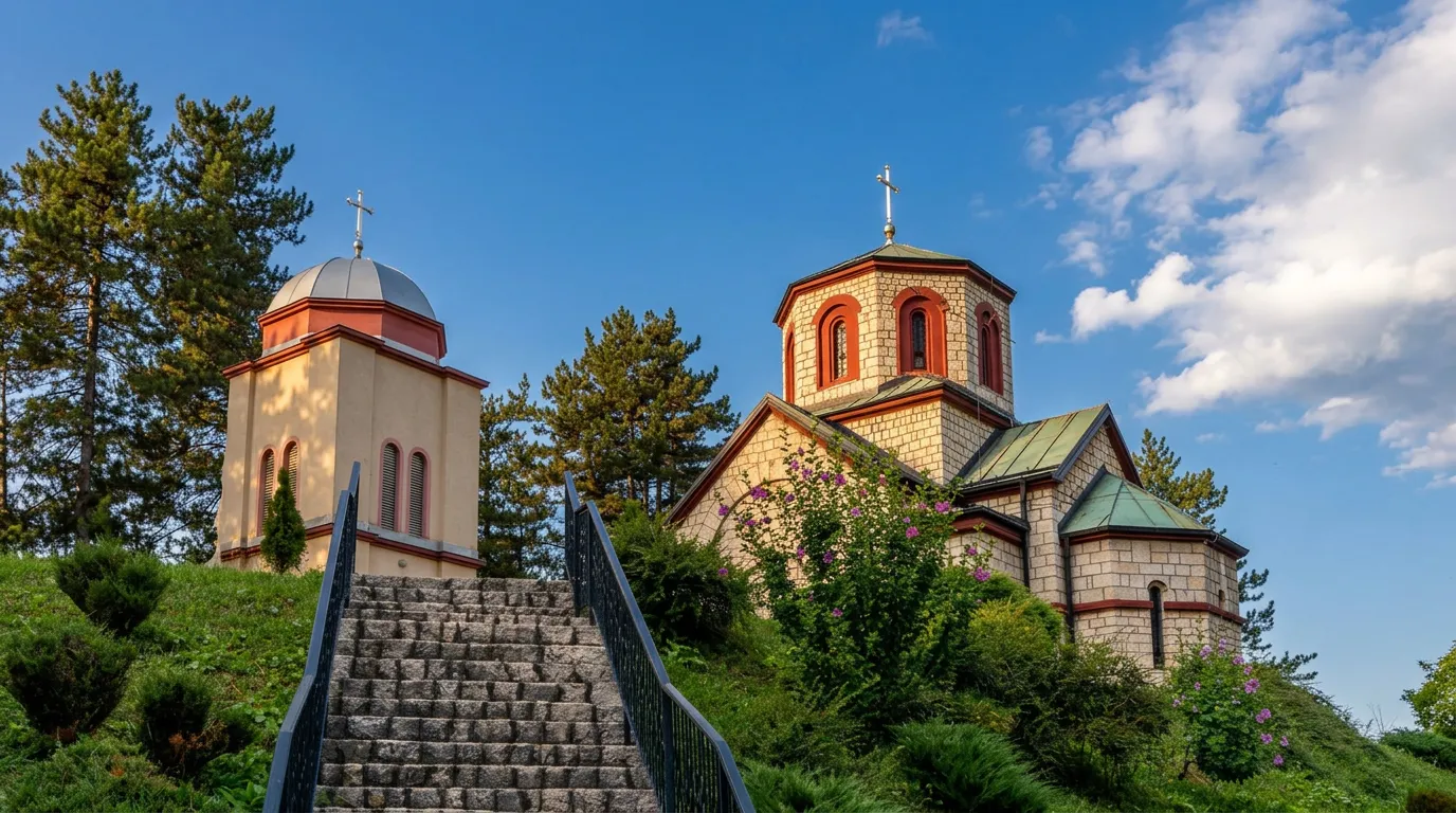 Pogled na kamene stepenice koje vode prema Hramu Pokrova Presvete Bogorodice u Tešnju, okruženom zelenilom pod plavim nebom