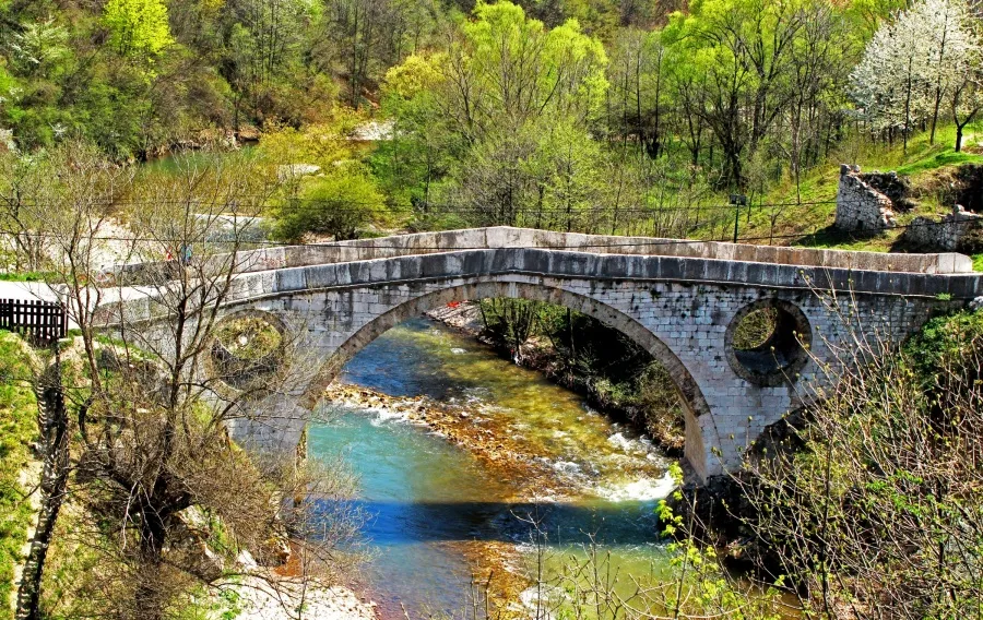 Kozija ćuprija u Sarajevu sa tirkiznom rijekom Mošćanicom ispod kamenih lukova, zelenilo oko mosta