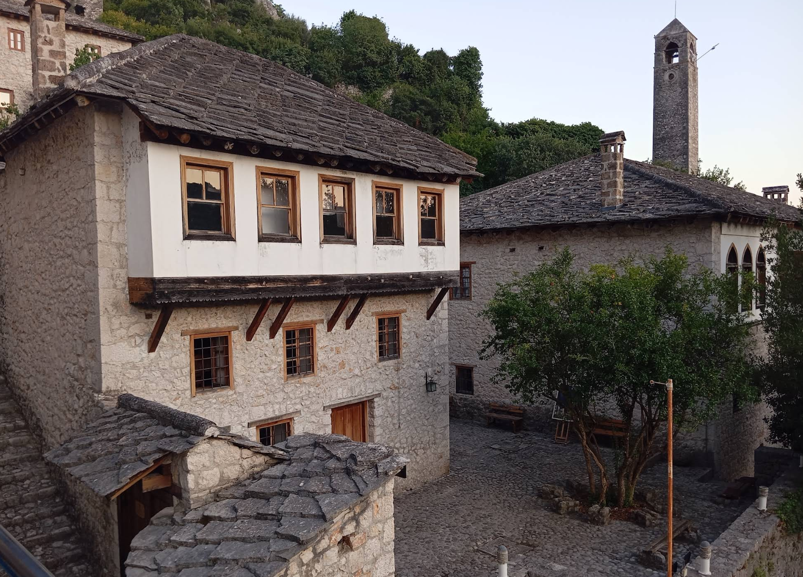  Dvorište Kuće Gavrankapetanovića u Počitelju, bijela fasada sa drvenim detaljima i kamenim popodom