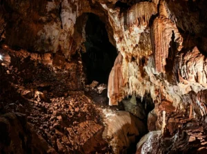 Pogled prema mračnom, dubokom prolazu i visokom svodu pećine Provalija, sa masivnim pećinskim nakitom, stalaktitima i stalagmitima na stjenovitim zidovima