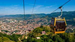 Hareket halindeki sarı Sarajevo teleferiği kabini, yolculara tüm Sarajevo vadisi ve çevredeki tepelerin açık manzarasını sunuyor