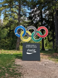 Büyük, renkli olimpiyat halkaları ve “Olimpik şehre hoş geldiniz” yazılı tabela, teleferiğin varış istasyonu yakınındaki ormanlık alanda yer alıyor