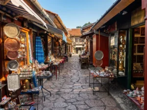 View along the cobbled street of Kazandžiluk in Baščaršija with copperware, džezvas, and traditional handicrafts displayed in front of old shops