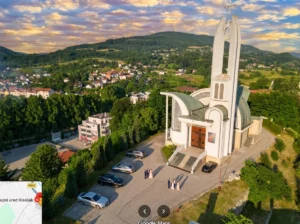 Veduta a volo d'uccello dell'architettura moderna della chiesa di Sant'Elia a Kiseljak con l'alto campanile bianco, il parcheggio ordinato davanti all'ingresso e il panorama dell'abitato sullo sfondo sotto il cielo autunnale